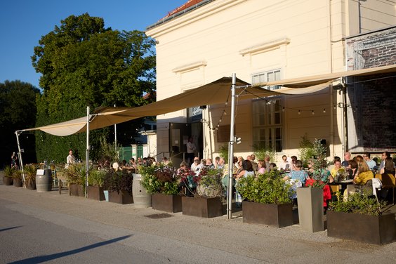 Blick auf den Gastgarten des Restaurants und Gäste der Feier.