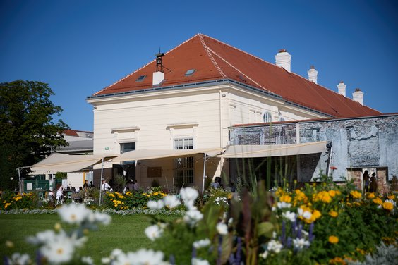 Blick auf den Gastgarten des Lokals mit Blumenwiese im Vordergrund.